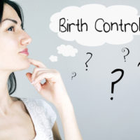 Woman next to a birth control sign.jpg.crdownload